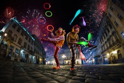 Night street circus performance whit two clowns, juggler. Festival city background. fireworks and Celebration atmosphere.