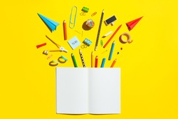 School notebook and stationery over yellow desk. Back to school abstract background.