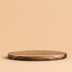Round wooden podium for food, products or cosmetics against bright brown background.