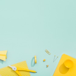 Creative, fashionable, minimalistic, school or office workspace with yellow stationery on cyan background. Flat lay.