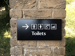 WC sign icon. Toilet symbol. Washroom sign on black background attached to brick wall