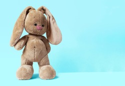 a cute baby soft toy bunny staying on a bright blue background
