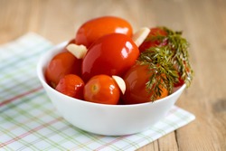 Pickled tomatoes with dill and garlic with white bowl