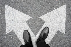Businessman in black shoes standing at the crossroad making decision which way to go. Decision making concept.