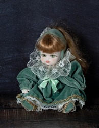Amazing realistic vintage toy with green eyes.The doll dressed in a green dress with lace. Selective focus. Porcelain.