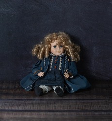 Amazing realistic vintage toy with blue eyes.The doll dressed in a blue dress and has a blond hair. Selective focus. Porcelain.