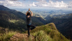 Woman doing Yoga on top of Little Adam's Peak in Ella, Sri Lanka