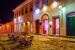 Night view of streets and houses of historical center with tables of restaurant in Paraty, Rio de Janeiro, Brazil.