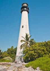 `front view, medium distance of a lighthouse on a tropical island surrounded by generic vegetation, on s sunny afternoon