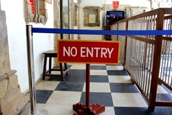 A no entry board suspended on the wooden board. Red colored no entry board on the floor.