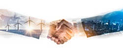 Concept of collaboration to change the world to reduce global warming,energy sources for renewable,sustainability by alternative energy.Double exposure of handshake of wind turbine and night city.