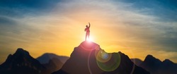 Silhouette of businessman celebrating raising arms on the top of mountain with over blue sky and sunlight.concept of leadership successful achievement with goal,growth,up,win and objective target.