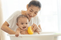 young Asian mother is Bathing with her newborn baby In Bathtub at home.Concept of newborn,baby,parenthood,motherhood,childhood,New life,maternity,love,new family member
