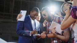 Ethnic celebrity man giving autographs to people on red carpet and makes photos