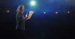 Medium close-up of an actress rehearsing a monologue in a theater while holding her script