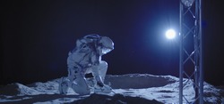 Medium shot of a young male astronaut kneeling on the Moon surface