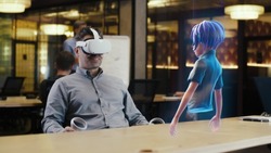 A man with virtual reality glasses uses a joystick to connect the video chat with an avatar of a girl via hologram in the metaverse. Augmented reality concept.