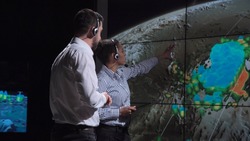 Group of two scientists observing and tracking hurricane on map and analyzing weather. Elements of this image furnished by NASA.