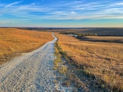 A gravel path leads to the horizon as the sun sets over the Tallgrass Prairie National Preserve in Kansas, USA