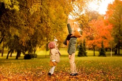 Autumn children boy and girl walking and playing in fall golden leaf park October season. Kids wearing knitted casual stylish clothes. Positive emotion. Copy space