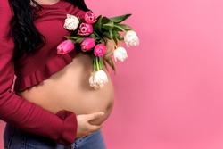pregnant woman with flowers on a monochrome background, waiting for a baby