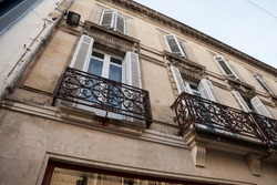 Facade of a typical old French residential building in Bordeaux, France, made of freestone, hosting flats, with a southwestern French architecture and some metal blinders.