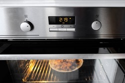 A working oven with a timer heats food. Inox oven. Chrome oven.