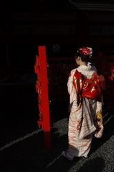 A devoted member of the public paying their traditional respect and a display of filial piety at the Fushimi-Inari Shrine, Kyoto, Japan.