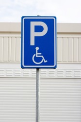 Blue disabled parking sign with a building in the background in Arnhem, Netherlands