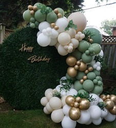 Sage, Gold and white birthday balloon arch backdrop on a grass wall              