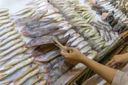Woman choosing fresh fish at seafood stall in marketplace