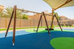 Swings in Dubai's public park, regular and nest type, above the rubber floor covered with the tensile shade canopy, summertime