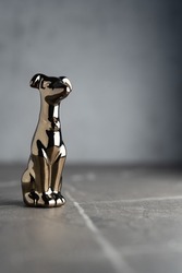 Сhrome-plated metal statuette of a dog, isolated on a dark neutral background	