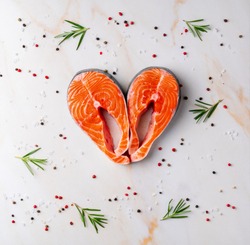 Food background, heart with salmon steaks and seasonings on white cream  table, flat lay.