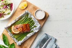 Foil pack dinner with fish. Fillet of salmon with asparagus, teriyaki sauce. Healthy diet food, keto diet, Mediterranean cuisine. Copy space, top view
