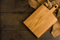 Wooden sturdy surface to prep on. Lightweight wood cutting board. Utensil for cooking food. Linen napkin. Oak chopping trivet. Overhead, copy space