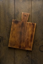Old dark wooden cutting board. Sturdy surface to prepare on. Cooking kitchenware. Rural utensil. Cookery appliances. Natural wood. Food background. Overhead. Vertical.