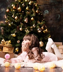 a beautiful girl lies on the floor by the Christmas tree and writes a wish