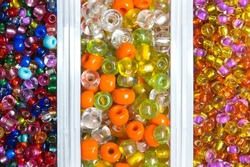 Glass seed beads for jewelry making in plastic containers in a variety of colors. Closeup, overhead view.