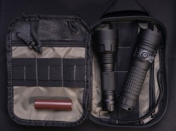 tactical bag with flashlights and battery on a dark background