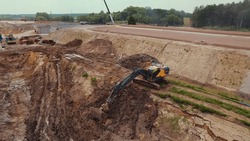 Long-reach crawler excavator moving earth at a construction site, digging the trenches for laying pipelines. Warsaw, Poland. . High quality photo