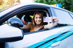 Woman with driving license. Driving school. Young beautiful woman successfully passed driving school test. Female smiling and holding driver's license.