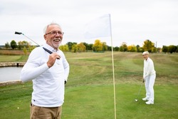 Portrait of an active senior man playing golf at the golf course and enjoying free time outdoors.
