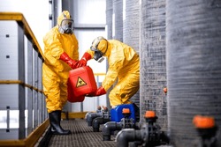 Factory workers carefully handling toxic and dangerous biohazardous waste in chemicals factory.