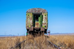 Old rusty, abandoned steam locomotive and train carriage. Abandoned railroad tracks in the desert.