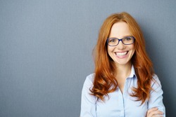Portrait of young red-haired woman wearing glasses against blue background