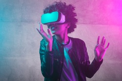 Cheerful girl with hands up wearing the virtual reality goggles. Cyan and magenta colors
