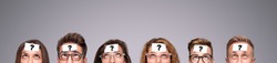 Group of puzzled young people with paper stickers with question mark on foreheads looking up while playing Who Am I game on gray background