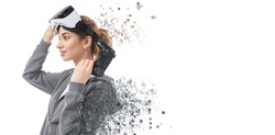 Female gamer with controller taking off VR headset and looking away while dispersing into pixels against white background