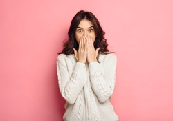 Portrait of amazed young woman over pink background